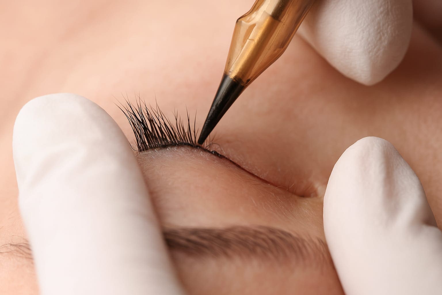 Präzise Pigmentierung beim Permanent Make Up Lidstrich in München – Nahaufnahme der Behandlung mit feiner Nadel und weißen Handschuhen für ein dauerhaft perfektes Ergebnis – Permanent Make Up München
